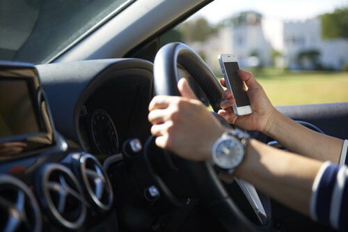 Mão humana no volante enquanto seguir celular. Créditos: banco de imagens