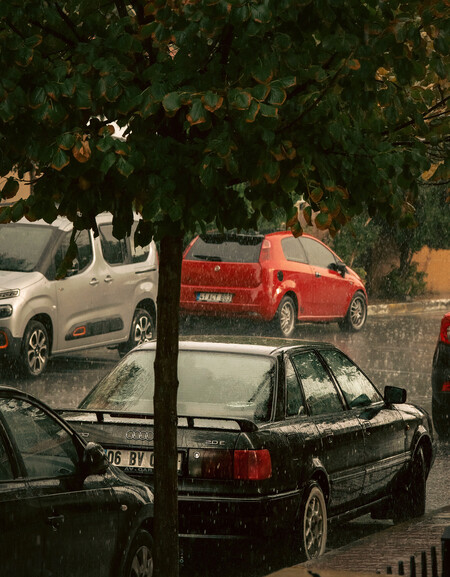 Lluvia sobre coches aparcados en la calle.