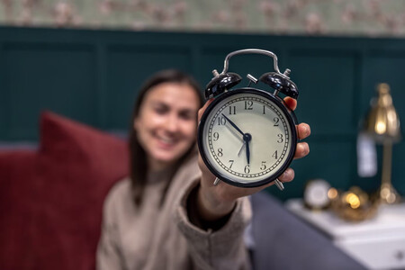 Chica sosteniendo un Reloj despertador antiguo, como símbolo del tiempo