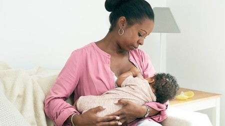 Mamá dando de mamar a su bebé em posición Cuna