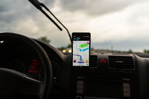 Aplicativo Waze aberto em celular apoiado no painel de veículo. Créditos: banco de imagens