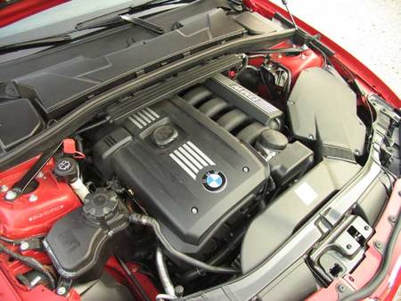 Imagen del vano motor del BMW Serie 1, con el motor de seis cilindros situado longitudinalmente. Sólo se ven cuatro