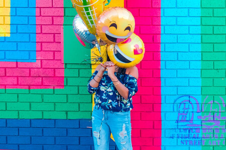 Chica joven sujetando globos que representan emojis, como símbolo de la emoción necesaria para que el marketing y la manipulación funcionen