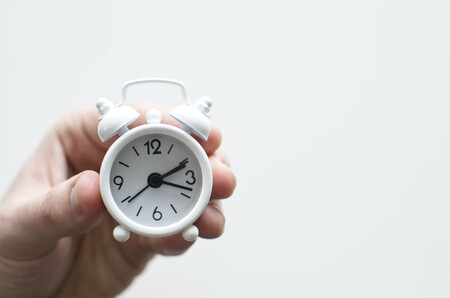 Mano sosteniendo un pequeño reloj despertador