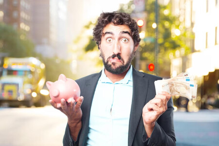 Un hombre con un fajo de billetes en una mano y una hucha de cerdito en otra