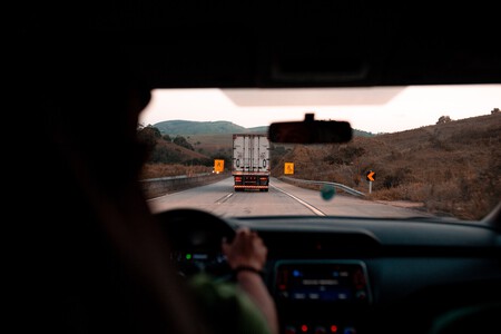 Conductor de coche circulando tras un camión en una carretera convencional