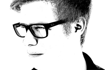 Chico joven con gafas mira a la izquierda.Blanco y negro.