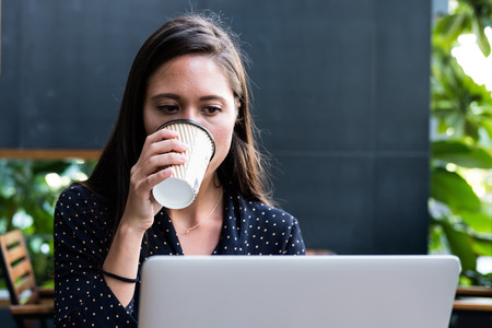 mujer ante ordenador bebiendo café