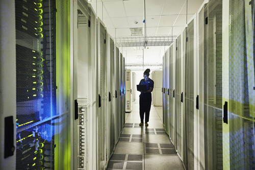 Mulher mexendo em computador dentro de datacenter. Créditos:Thomas Barwick/Getty Images