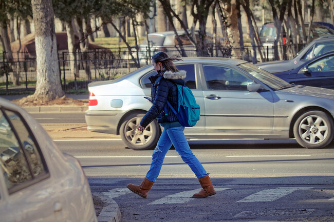 Mujer Cruzando La Calle Y Mirando El Movil