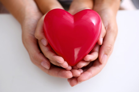 Manos del padre y la madre sosteniendo un corazón