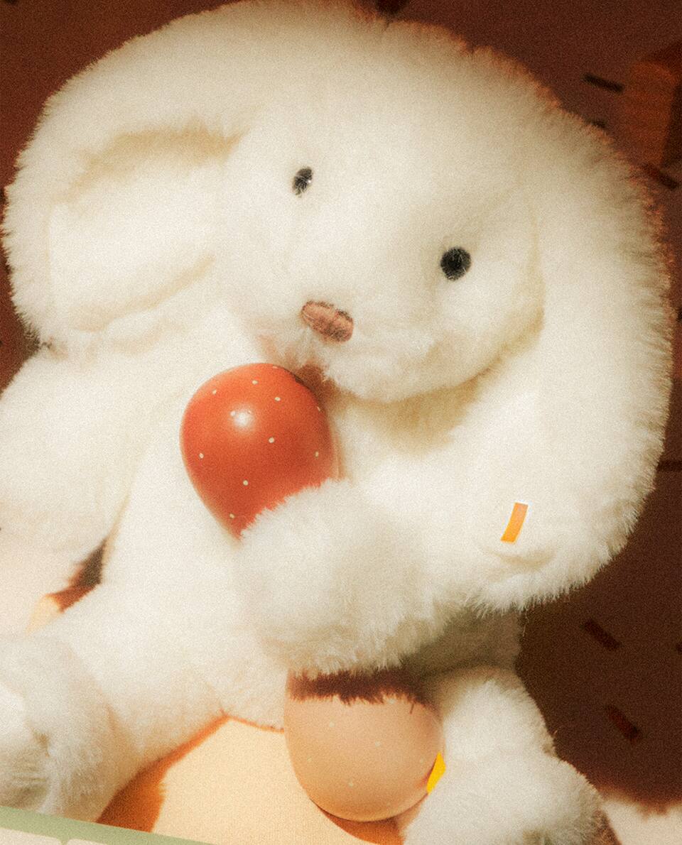 Peluche con forma de conejo blanco sentado.