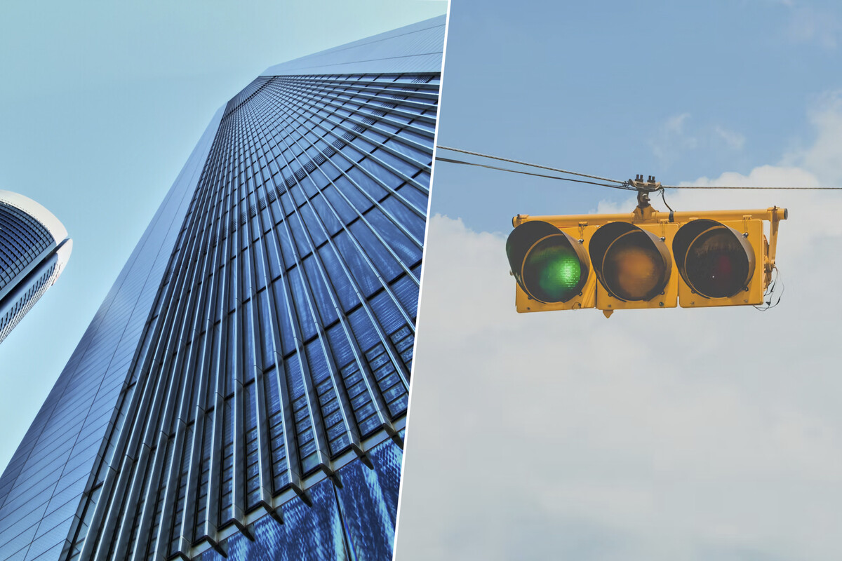 The image is split into two parts. On the left side, there is a towering modern skyscraper with a glass facade that reflects the sky, shown from a low angle looking upwards, emphasizing its height and sleek architectural design. On the right side, there is a close-up view of a yellow traffic light suspended by wires against a partly cloudy sky, with the green light illuminated, signaling that vehicles may proceed. The contrast between the urban structure and the traffic signal highlights elements of city life.