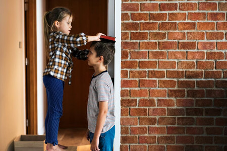 Dos niños midiéndose la altura en el marco de una puerta