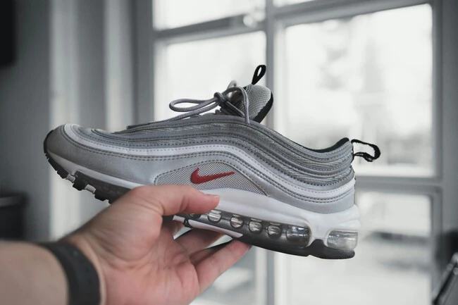 Persona Sosteniendo Zapatillas Deportivas Nike Grises Y Blancas