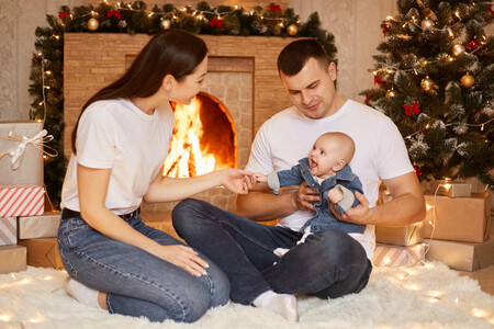 Portrait Of Happy Family Father Mother And Toddler Daughter Posing At Fireplace And Christmas Tree At Home Being Happy To Celebrate Winter Holidays Together Happy New Year