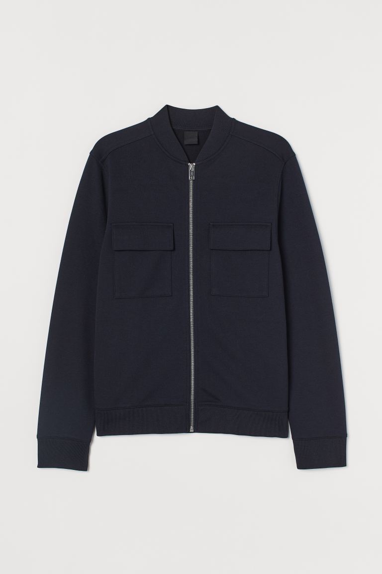 Cazadora bomber en punto grueso con cuello elevado corto y cremallera delante. Bolsillos superiores con solapa, bolsillos al bies discretos y remate en punto elástico en puños y bajo.