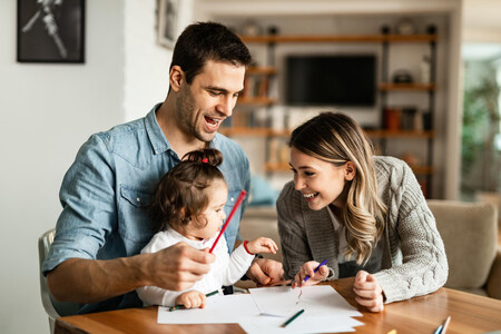 Happy Parents And Their Small Daughter Having Fun While Coloring On The Paper