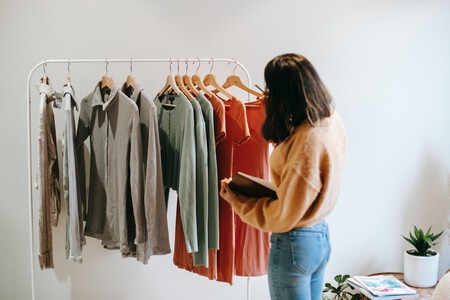 Mujer de espaldas ordena vestidos.