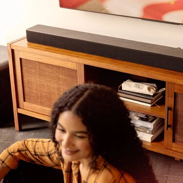 Klipsch Flexus Core 300 Bk And Sub 200 In Focus In Sunny Living Room With American Flag On Tv And Woman In Blurred Foreground 2000x1000