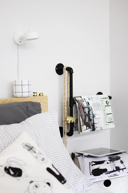 Una buena idea: una tubería junto a la cama como revistero y joyero