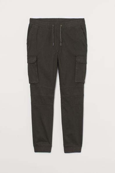 Joggers en sarga de algodón con cintura elástica y cordón de ajuste. Modelo con bolsillos al bies, bolsillos traseros y bolsillos en las perneras con solapa y botones de presión.