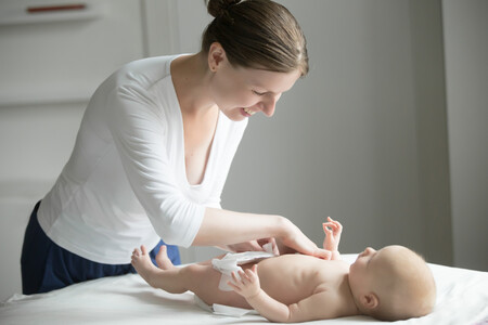 Portrait Of Young Smiling Beautiful Woman Fixing Diaper On Newborn