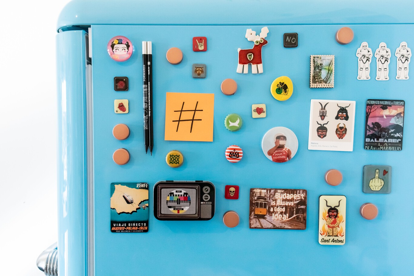 Detalle de varios imanes de colores pegados en la puerta de una heladera, con fotos y notas