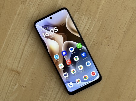 Foto del Motorola Moto G55 5G con la pantalla encendida sobre una mesa de madera