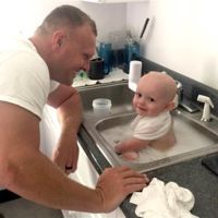 Un oficial de policía baña a un bebé que estaba cubierto en vómito tras arrestar a su madre que conducía borracha